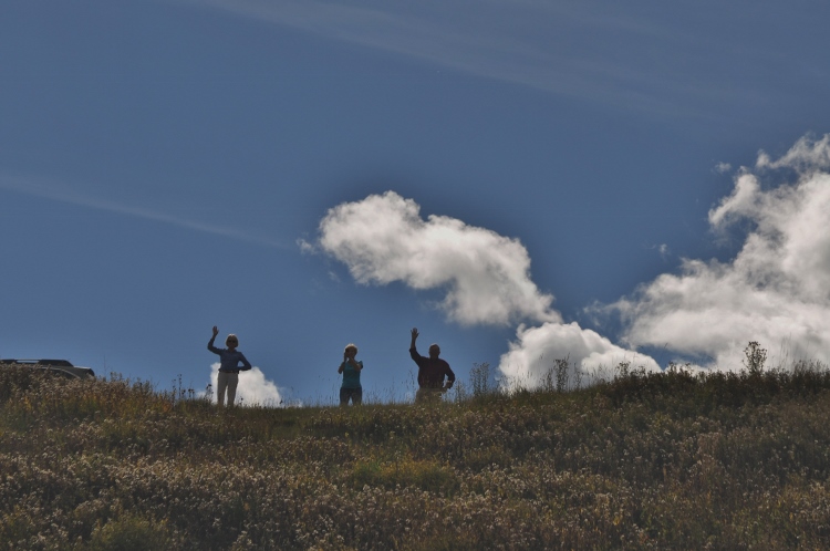 people on hill waving at train
